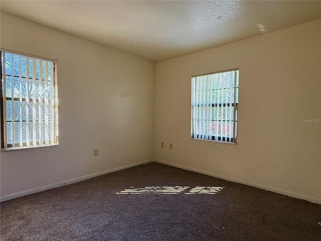 empty room featuring carpet and baseboards