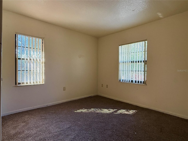 carpeted empty room featuring baseboards and a textured ceiling