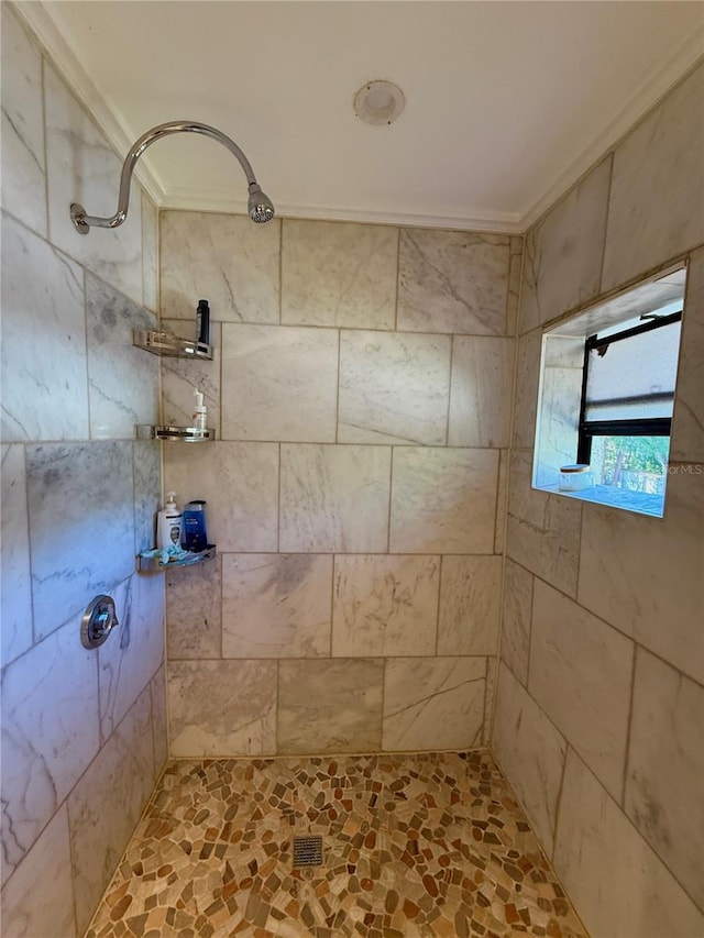 bathroom with a tile shower and ornamental molding