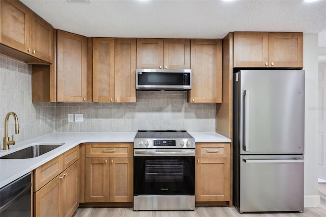 1957 Deloy Dr, Daytona Beach, FL 32119 - kitchen featuring appliances with stainless steel finishes, a sink, light countertops, brown cabinetry, and tasteful backsplash