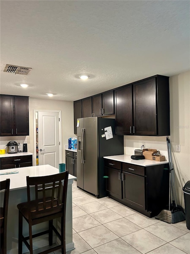4427 Blackbird St, Kissimmee, FL 34746 - kitchen featuring light countertops, stainless steel refrigerator with ice dispenser, light tile patterned floors, a breakfast bar, and recessed lighting