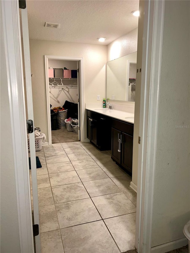 4427 Blackbird St, Kissimmee, FL 34746 - full bathroom with vanity, a walk in closet, tile patterned floors, and a textured ceiling