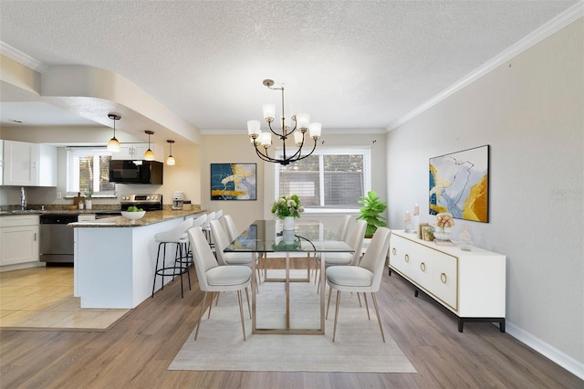 1948 Conway Rd Unit 8, Orlando, FL 32812 - dining space featuring a chandelier, light wood-style flooring, crown molding, a textured ceiling, and baseboards