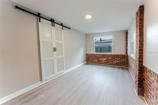 635 San Lanta Cir, Sanford, FL 32771 - unfurnished living room featuring a barn door, wood finished floors, brick wall, and baseboards