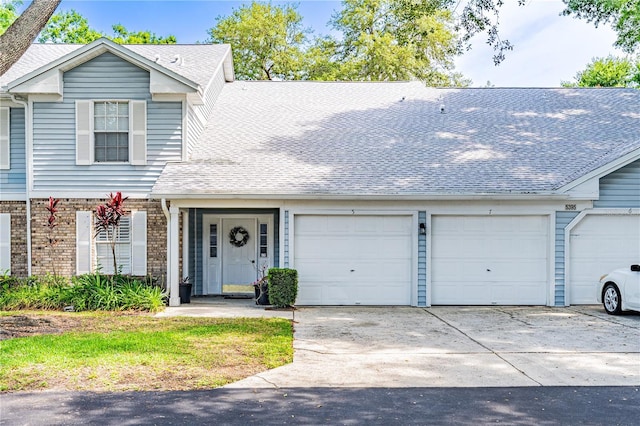 5395 Dover Village Ln Unit 305, Orlando, FL 32812 - view of front of house with a garage, concrete driveway, brick siding, and a shingled roof