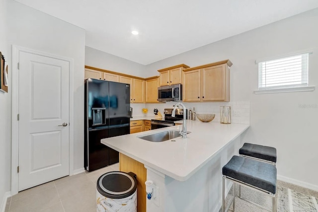 2110 Hillcrest St, Orlando, FL 32803 - kitchen with appliances with stainless steel finishes, light brown cabinets, a peninsula, a kitchen bar, and light countertops