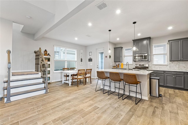 15358 Arcadia Bluff Loop, Winter Garden, FL 34787 - kitchen featuring stainless steel appliances, gray cabinetry, light wood-type flooring, a kitchen breakfast bar, and recessed lighting