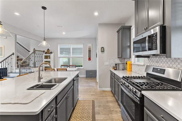15358 Arcadia Bluff Loop, Winter Garden, FL 34787 - kitchen with appliances with stainless steel finishes, a sink, decorative backsplash, light wood-type flooring, and decorative light fixtures