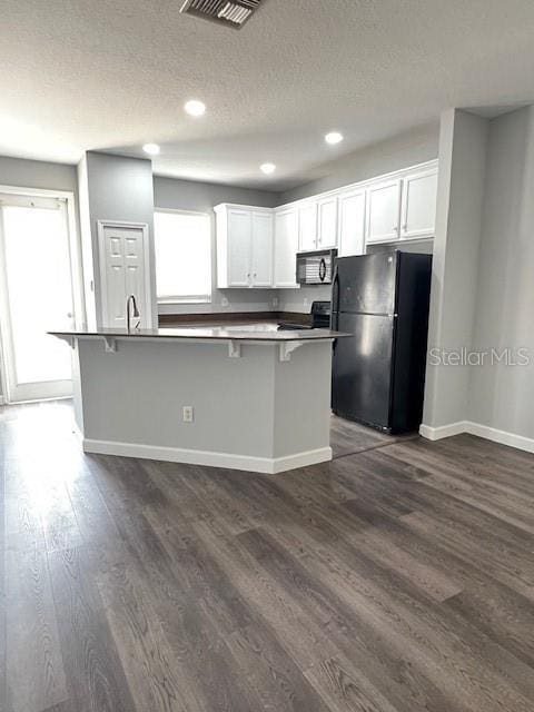 14531 Pleach St, Winter Garden, FL 34787 - kitchen featuring black appliances, white cabinetry, dark wood-type flooring, recessed lighting, and a textured ceiling