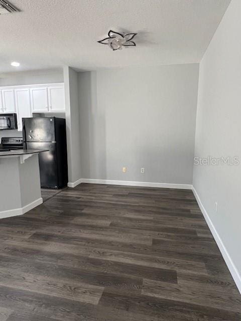 14531 Pleach St, Winter Garden, FL 34787 - kitchen featuring black microwave, freestanding refrigerator, white cabinetry, dark wood finished floors, and a textured ceiling