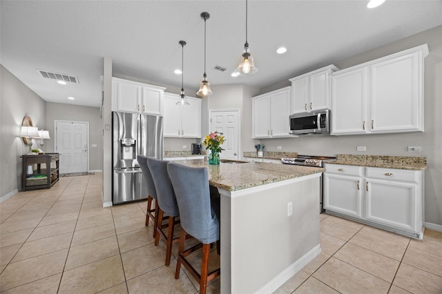 646 Marsh Reed Dr, Winter Garden, FL 34787 - kitchen featuring stainless steel appliances, light tile patterned floors, white cabinetry, light stone counters, and a kitchen island with sink