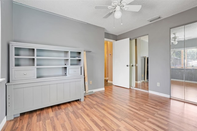 106 8th St, Lake Hamilton, FL 33851 - unfurnished bedroom with wood finished floors, a textured ceiling, baseboards, two closets, and ceiling fan