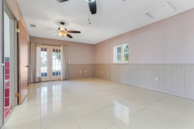 106 8th St, Lake Hamilton, FL 33851 - tiled empty room featuring french doors, a ceiling fan, a wainscoted wall, a textured ceiling, and attic access