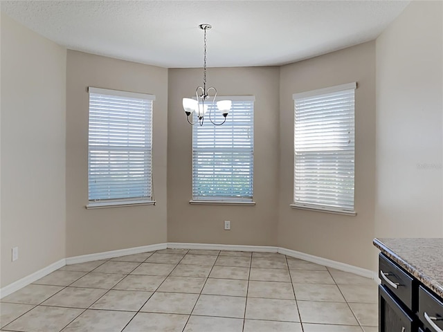 unfurnished dining area with a chandelier, light tile patterned floors, and baseboards
