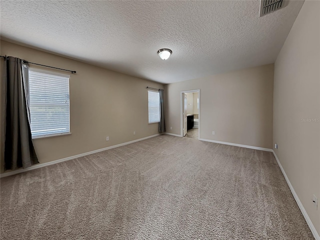 unfurnished room with a textured ceiling, baseboards, and light carpet