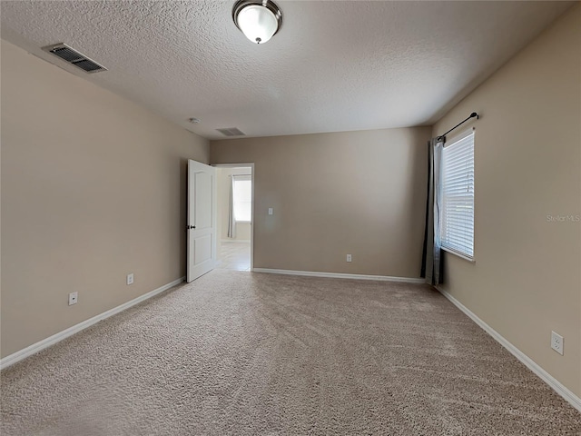 spare room featuring a textured ceiling, baseboards, and light colored carpet