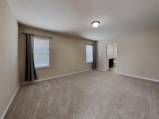 empty room with baseboards, light colored carpet, and a textured ceiling