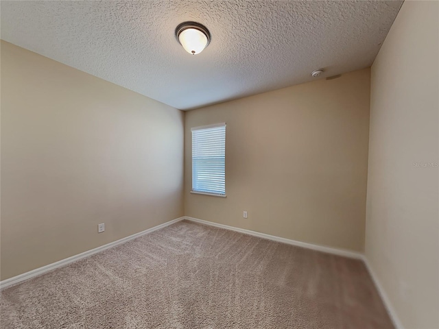 carpeted empty room featuring a textured ceiling, baseboards, and a smoke detector