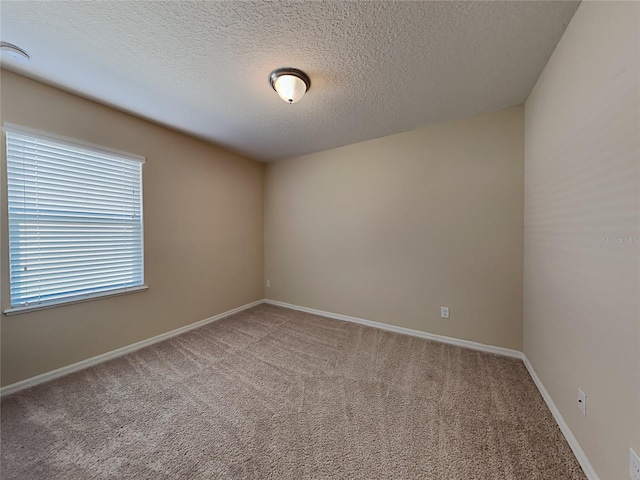 unfurnished room with carpet flooring, a textured ceiling, baseboards, and a smoke detector