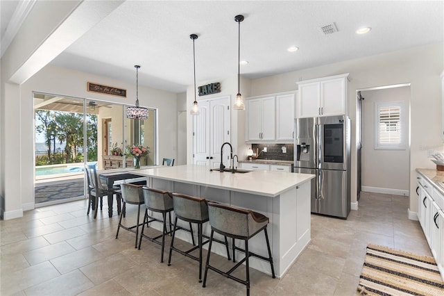 557 Lake Cove Pointe Cir, Winter Garden, FL 34787 - kitchen featuring stainless steel fridge with ice dispenser, a sink, baseboards, decorative backsplash, and white cabinetry