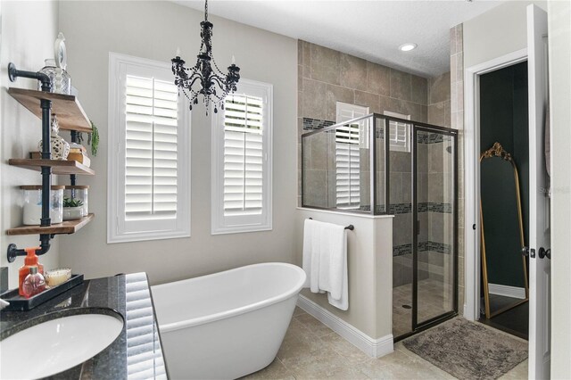 557 Lake Cove Pointe Cir, Winter Garden, FL 34787 - bathroom with a shower stall, a chandelier, a sink, a freestanding tub, and baseboards