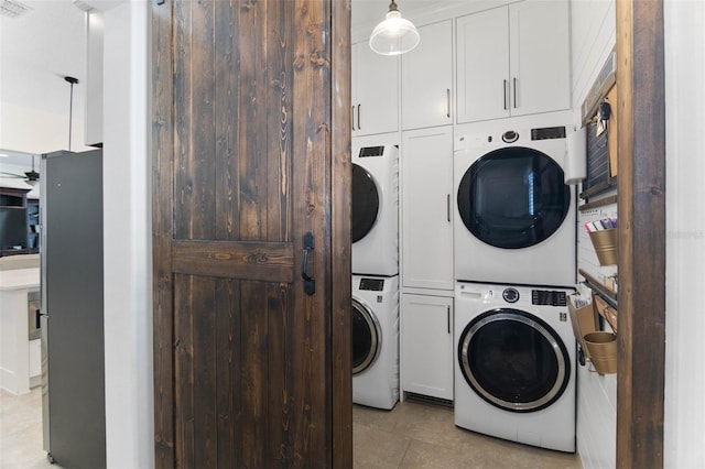 557 Lake Cove Pointe Cir, Winter Garden, FL 34787 - laundry area featuring stacked washing machine and dryer, cabinet space, and light tile patterned floors