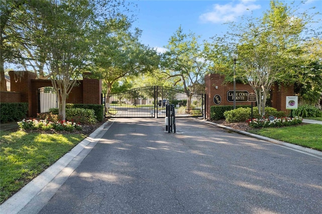 557 Lake Cove Pointe Cir, Winter Garden, FL 34787 - view of asphalt road with a gate, curbs, a gated entry, and street lighting