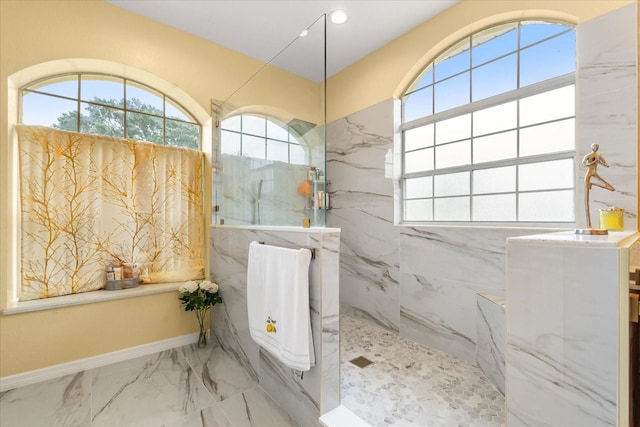 full bath with plenty of natural light, a marble finish shower, marble finish flooring, baseboards, and recessed lighting