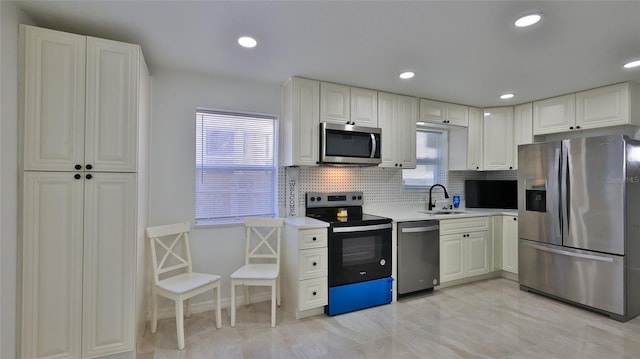 326 Hobart Ave, Daytona Beach, FL 32114 - kitchen featuring appliances with stainless steel finishes, a sink, backsplash, light countertops, and white cabinetry