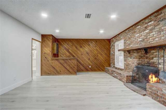 3100 Las Palmas Dr, Titusville, FL 32780 - unfurnished living room featuring baseboards, wood finished floors, recessed lighting, wood walls, and a brick fireplace