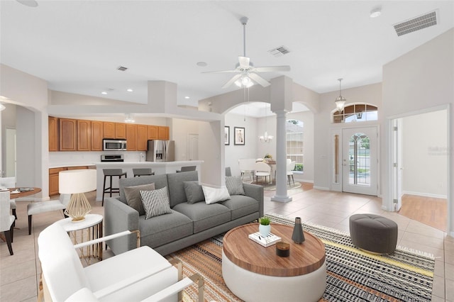 9330 Shadow Pinar Ct, Orlando, FL 32825 - living room featuring arched walkways, light tile patterned floors, ceiling fan, decorative columns, and a towering ceiling