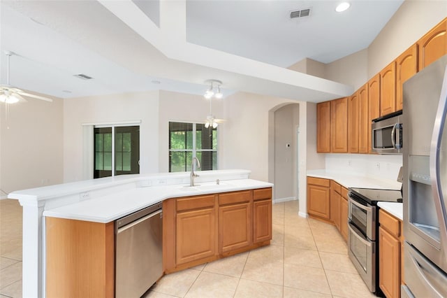 9330 Shadow Pinar Ct, Orlando, FL 32825 - kitchen with stainless steel appliances, a sink, ceiling fan, arched walkways, and light tile patterned flooring