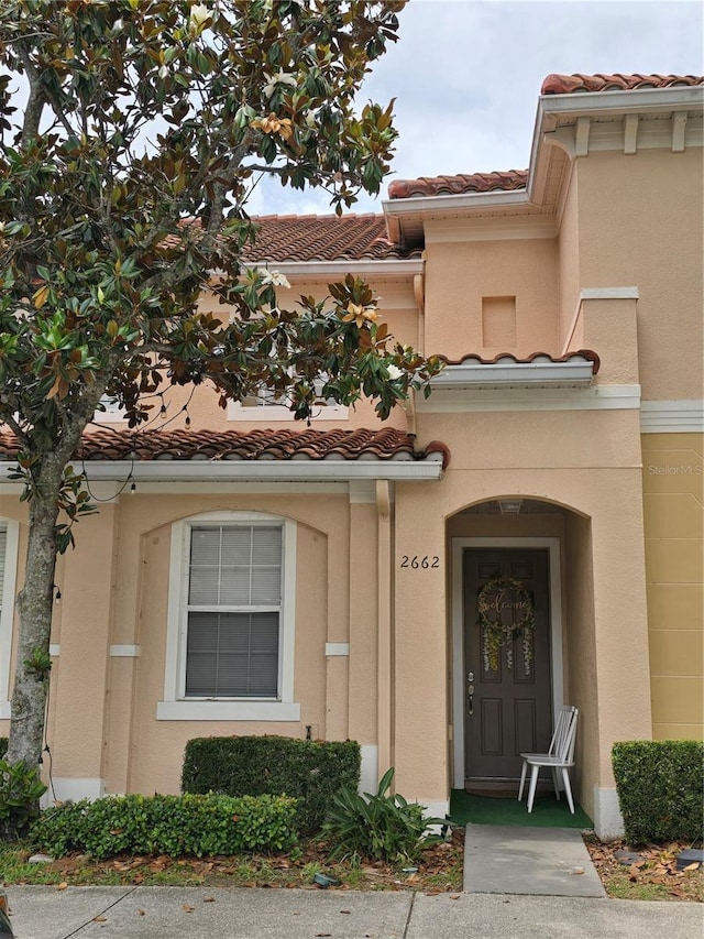 doorway to property with a tile roof and stucco siding