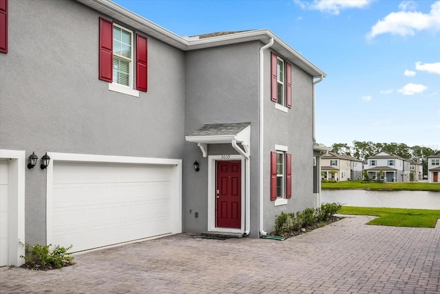 3039 Meleto Blvd, New Smyrna Beach, FL 32168 - view of front of home with an attached garage, stucco siding, a water view, decorative driveway, and a residential view