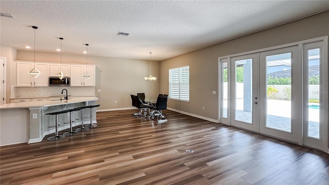 9917 Summerlake Groves St, Winter Garden, FL 34787 - kitchen with stainless steel microwave, dark wood-type flooring, a textured ceiling, white cabinetry, and light countertops