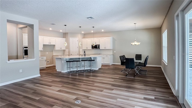 9917 Summerlake Groves St, Winter Garden, FL 34787 - kitchen featuring stainless steel appliances, dark wood-type flooring, white cabinets, an island with sink, and light countertops