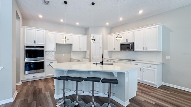 9917 Summerlake Groves St, Winter Garden, FL 34787 - kitchen with appliances with stainless steel finishes, a sink, dark wood-style flooring, an island with sink, and recessed lighting