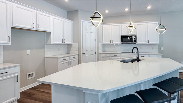 9917 Summerlake Groves St, Winter Garden, FL 34787 - kitchen featuring stainless steel microwave, a sink, baseboards, tasteful backsplash, and dark wood finished floors
