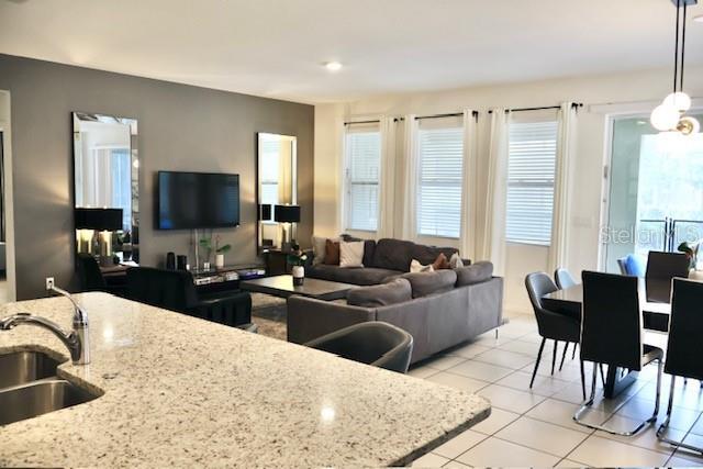 kitchen with a sink, light tile patterned floors, open floor plan, and hanging light fixtures