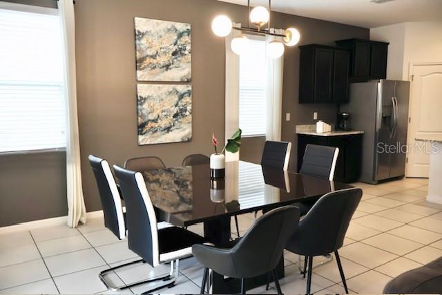 dining area featuring healthy amount of natural light, light tile patterned floors, a chandelier, and baseboards