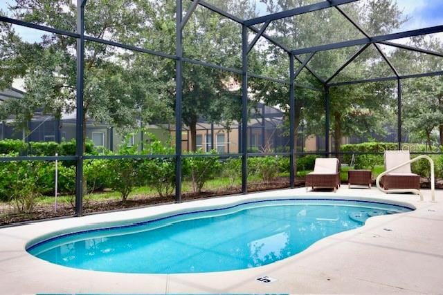 swimming pool featuring a patio and glass enclosure