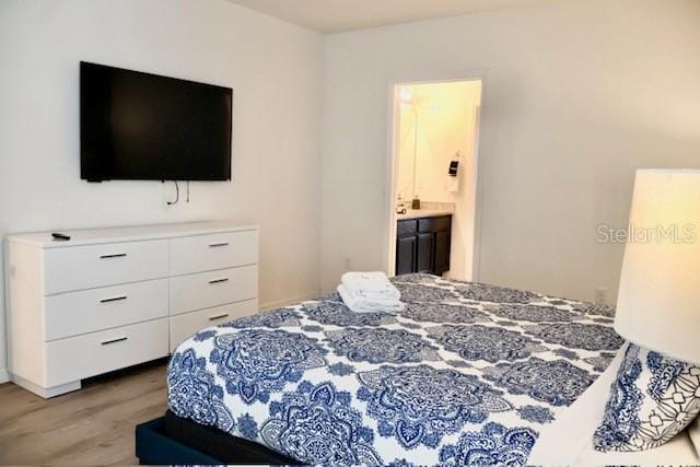 bedroom with wood finished floors and connected bathroom