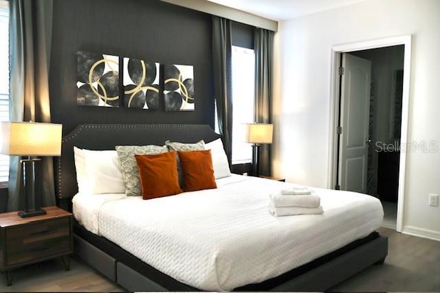 bedroom featuring multiple windows, wood finished floors, and baseboards