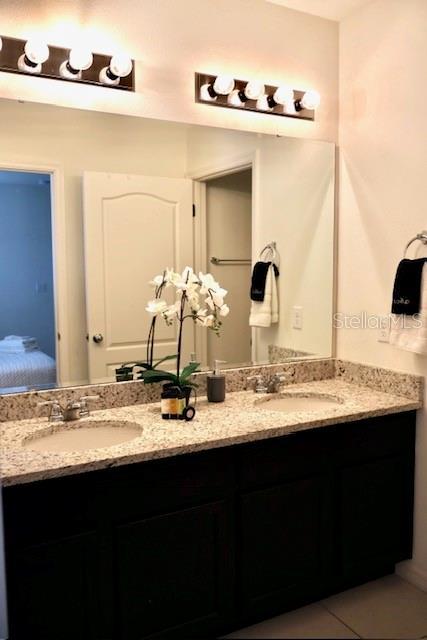 ensuite bathroom featuring double vanity and tile patterned floors