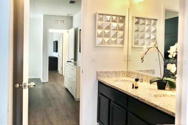 full bathroom with wood finished floors, double vanity, and baseboards