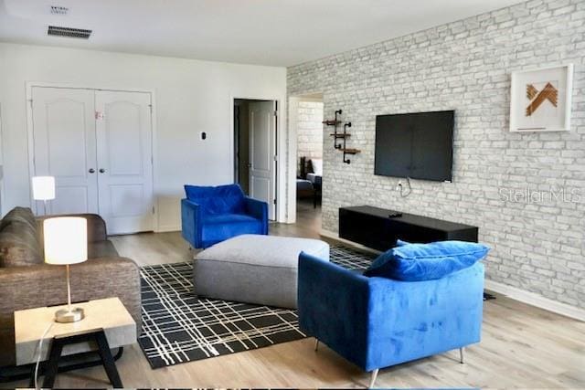 living room with brick wall and wood finished floors