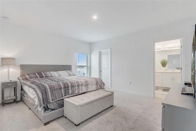 bedroom featuring light carpet, connected bathroom, and baseboards