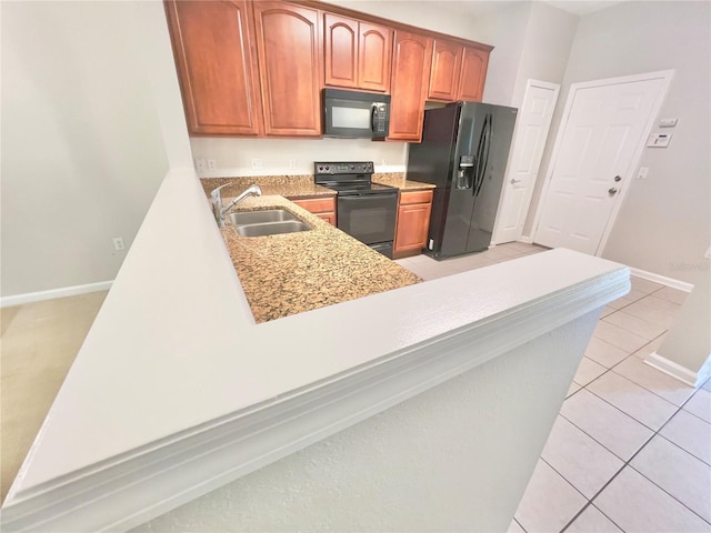 kitchen with black appliances, a sink, light tile patterned floors, baseboards, and light stone counters