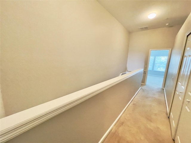 corridor with an upstairs landing, light carpet, and baseboards