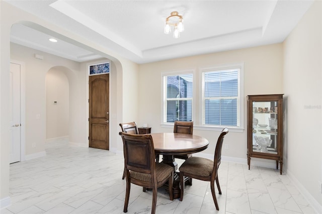 16696 Otterchase Ln, Winter Garden, FL 34787 - dining room with arched walkways, a raised ceiling, light marble finish floors, recessed lighting, and baseboards